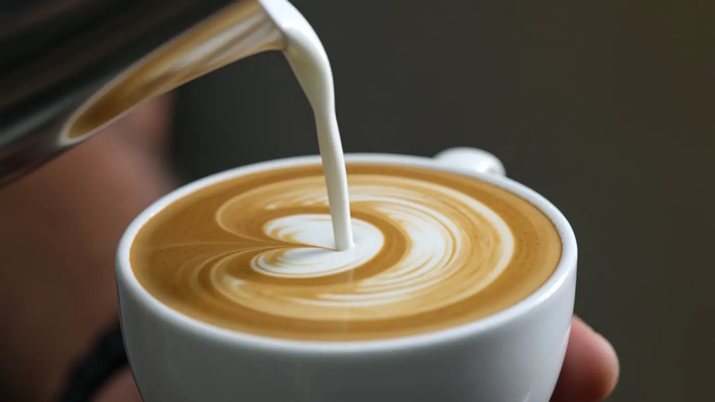 Milk poured into a latte forming a heart
