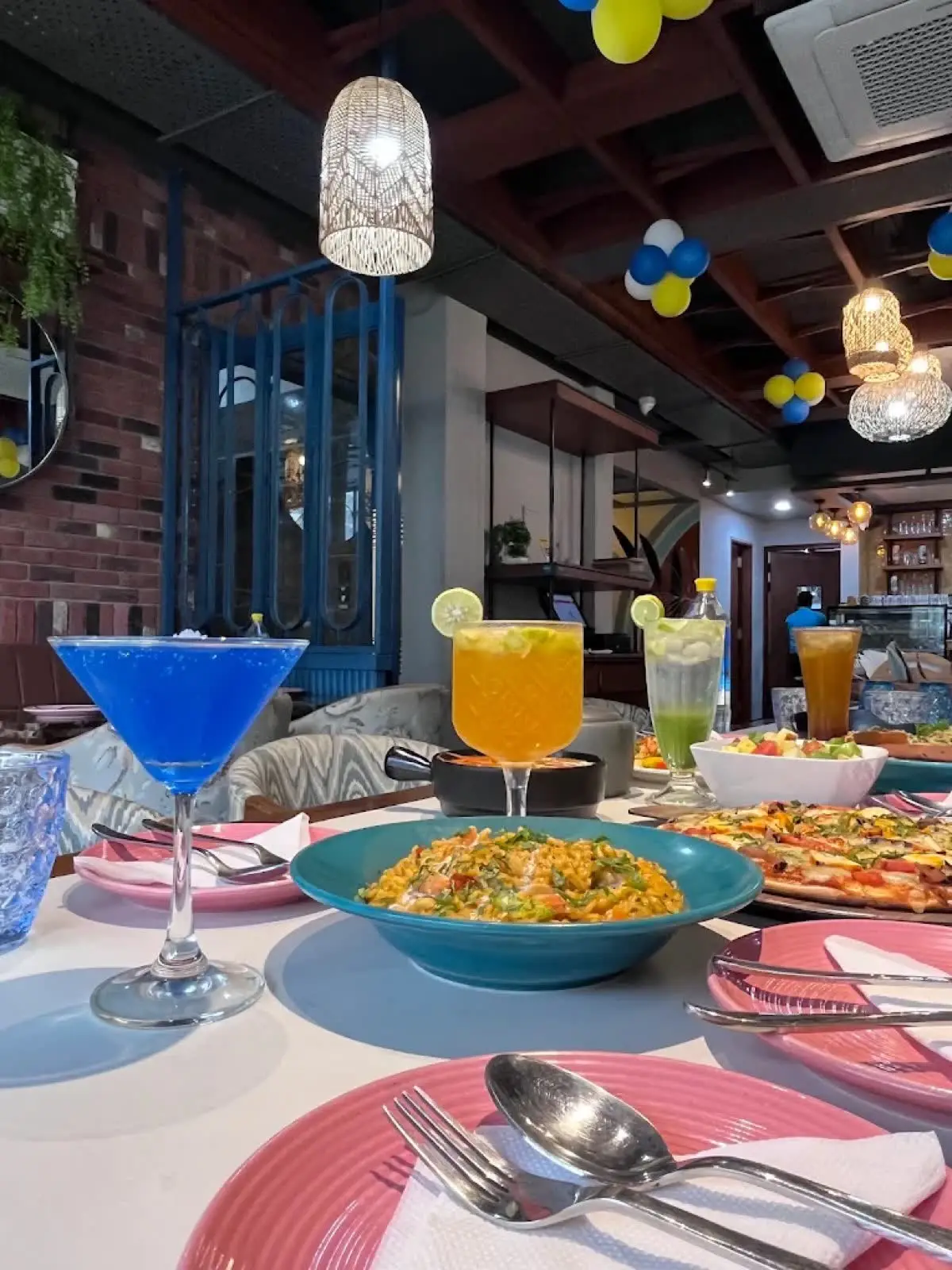 A table set with pizza, rice and mocktails under party balloons