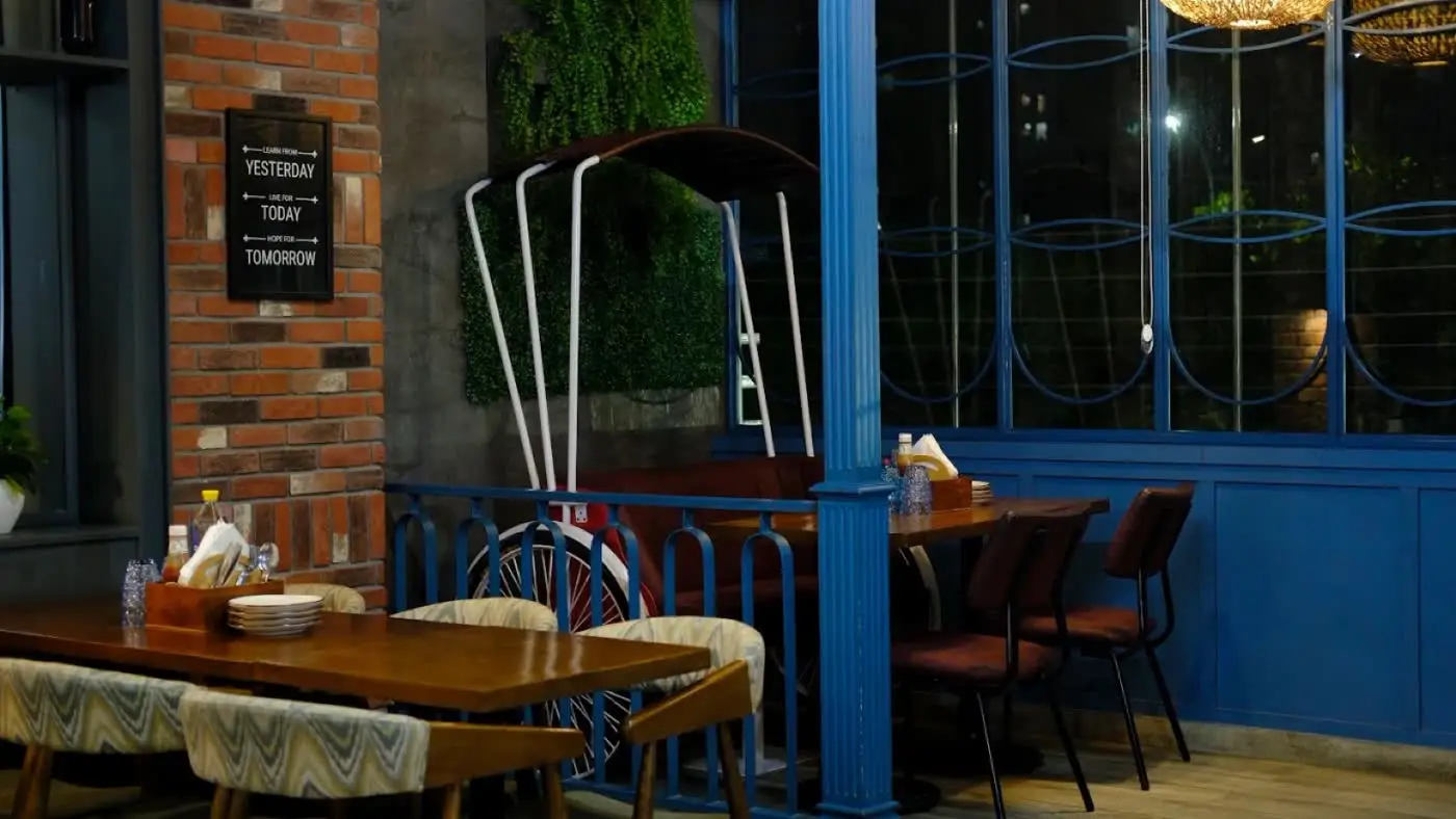 A quiet blue corner with a cycle-shaped arch and wooden tables