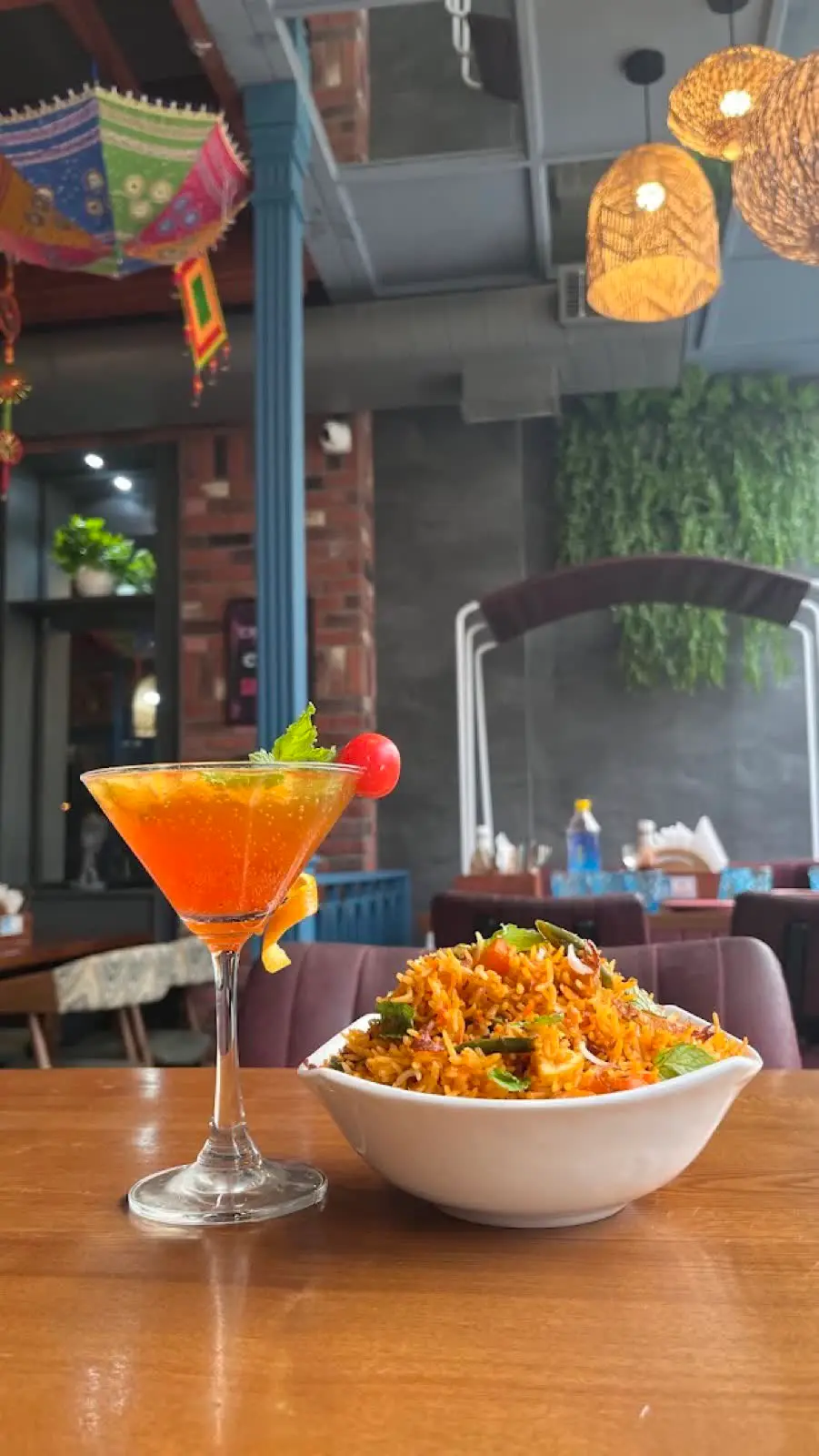 A mocktail and a bowl of spiced pasta on a wooden table